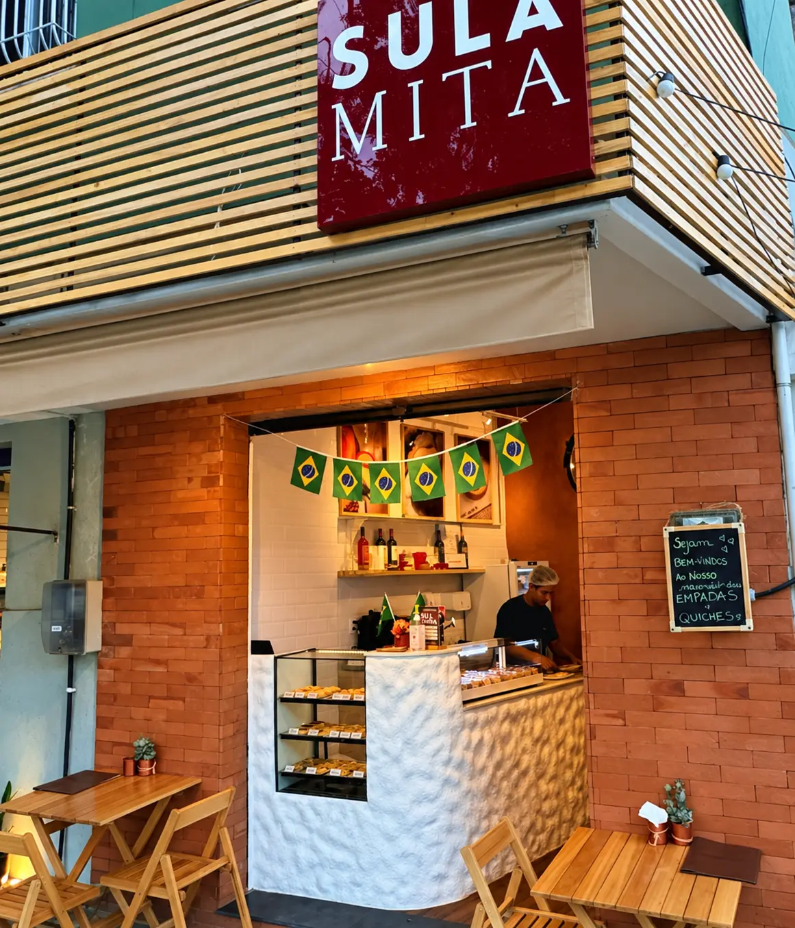Fachada do Bistrô Sulamita iluminada, com clientes e equipe